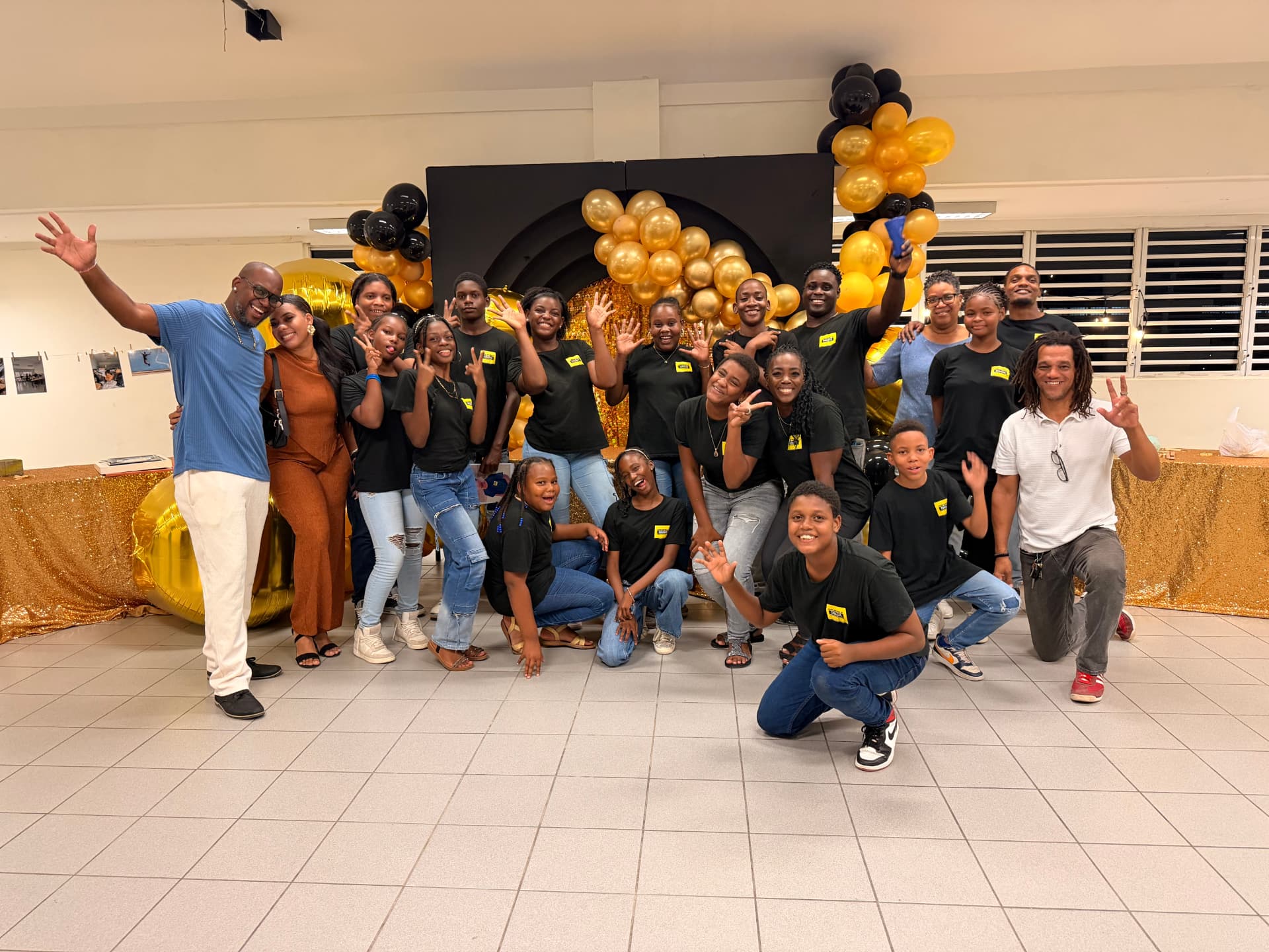 Groepsfoto van jongeren, ouders en begeleiders tijdens een HUNTU-evenement met gouden ballonnen