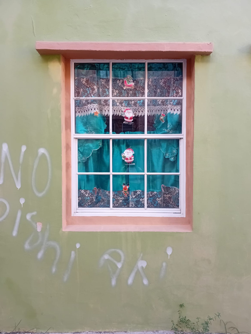 Raam met gordijnen en kerstfiguren in een groene muur — foto gemaakt door een jongere tijdens de workshop