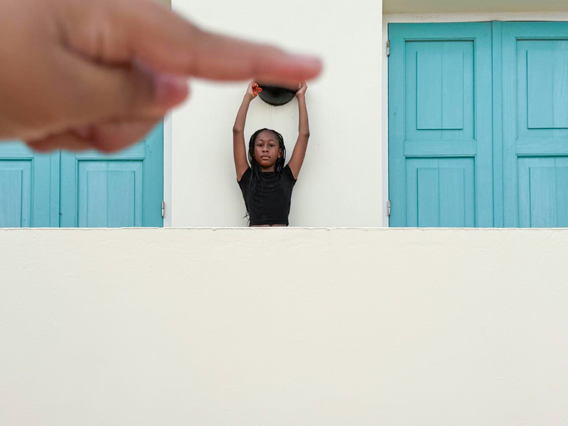Meisje met een hoed voor turquoise deuren, een hand wijst in beeld — foto gemaakt door een jongere tijdens de workshop