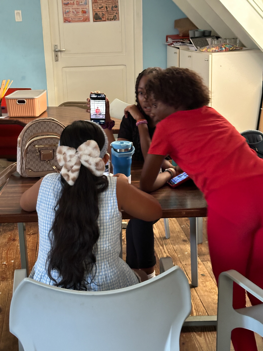 Drie jongeren bekijken samen een foto op een telefoon in het atelier