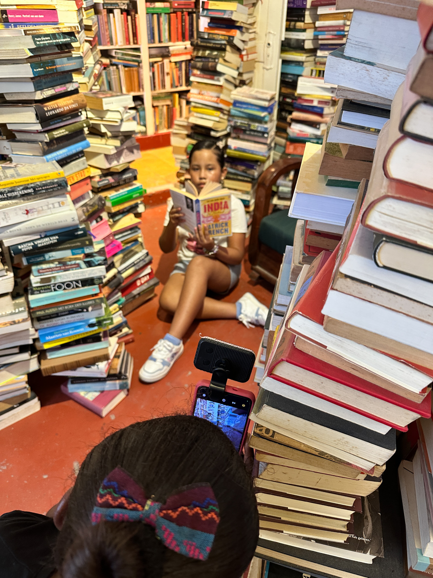 Meisje leest tussen de boeken terwijl een deelnemer haar fotografeert